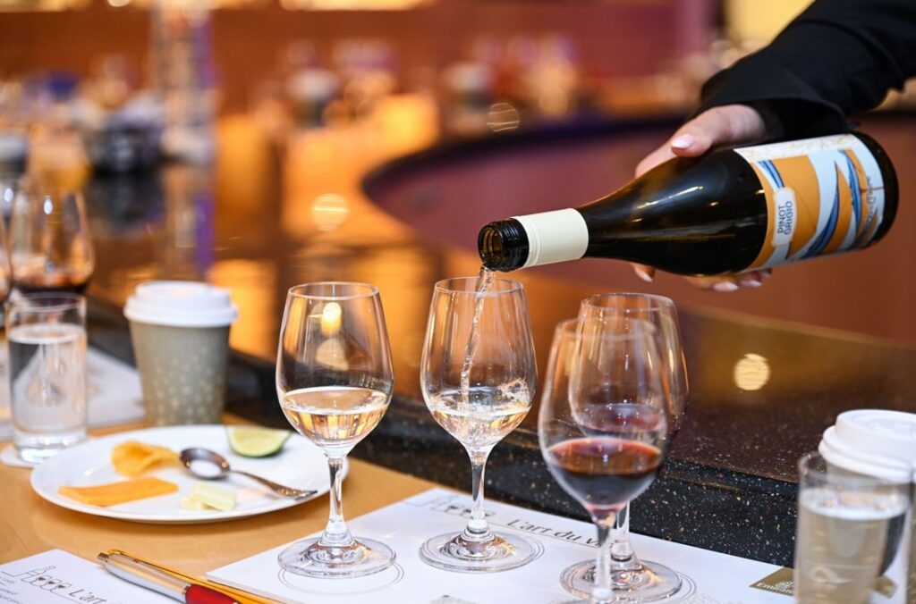 Letušky a stevardi společnosti Emirates si opět rozšíří své obzory. Aerolinka nedávno zahájila specializované kurzy vín „L'art du vin“, jejichž cílem je zpříjemnit cestujícím zážitek v oblacích, kde jim palubní personál představí kolekci uznávaných vín a vzácných odrůd z vinného sklepa Emirates či poradí při párování s jídlem. Kurz „L'Art du Vin“ se skládá ze tří modulů: L'art du vin - Introduction, L'art du vin - Business Class a L'art du vin - First Class. Výuka probíhá v učebně imitující charakteristický salonek A380, která je doplněna vitrínami se studijním materiálem, tedy šampaňským, víny, sklem a výběrem knih o enologii a vinařství. Kurz doposud absolvovalo více než 1 000 palubních průvodčích a do roku 2026 jich chce Emirates vyškolit dalších 22 000. L'art du vin pro všechny úrovně zkušeností Jednotlivé moduly „L'art du vin“ jsou pečlivě navrženy tak, aby vyhovovaly různým úrovním znalostí a zkušeností palubního personálu. Úvodní kurz L'art du vin - Introduction je určen nově přijatým členům palubní posádky a zahrnuje základní informace o vinném programu aerolinek, základní informace o víně a jeho výrobě, degustaci bílého a červeného vína, úvod do šumivých vín, techniky doporučování vhodných vín a správné postupy při jejich servírování. Kurz L'art du vin“ - Business Class dále prohlubuje znalosti zkušenějších palubních průvodčích. Seznámí se s exkluzivním vinným sklepem Emirates, klíčovými vinařskými oblastmi světa a vlivem podnebí na charakter vín. Součástí kurzu je také úvod do šampaňského a portského a výuka základů párování vína s jídlem, doplněná o cílené degustace. Během školení mohou účastníci využívat exkluzivní aplikaci L'art du vin, která slouží jako profesionální průvodce vínem. Aplikace umožňuje vést si vlastní degustační poznámky a připravit se tak na interakci se zákazníky během letů. Kurz L'art du vin - First Class navazuje na znalosti získané v Business Class a nabízí hlubší vhled do světa prestižních vín Premier a Grand Cru Classé. Tento pokročilý kurz se zaměřuje na prestižní klasifikaci Bordeaux 1855 a podrobně zkoumá vína Premier Cru Classé, jako je Château Cos d'Estournel 2006 ze St-Estèphe, a burgundská vína Grand Cru, včetně proslulého Bâtard-Montrachet 2013 od Louise Latoura. Program se neomezuje pouze na Bordeaux a Burgundsko, ale zahrnuje ikonická vína z celého světa. Palubní personál získá odborné znalosti o výjimečných vínech ze Španělska, jako je Vega Sicilia Unico 2006 z Ribera del Duero, a z Itálie, například Ornellaia 2012 z Bolgheri v Toskánsku čio kalifornském Opus One 2012 z Napa Valley. Dále nabízí podrobné seznámení se šampaňským Dom Pérignon, sladkým Château d'Yquem ze Sauternes a portskými víny od renomovaných domů, jako jsou Graham's, Dow's a Sandeman. Lekce o párování vína s jídlem posouvají odborné znalosti palubního personálu a učí je, jak správně vyvážit kyselost, slanost, sladkost a umami, či jak doporučit vína, která dokonale doplní různé druhy sýrů. Kurzy L'art du Vin vedou vybraní členové palubního personálu, označovaní jako „vyslanci vína“, kteří získali oficiální certifikáty WSET Level 2 a 3 od The Wine & Spirit Education Trust. Výjimečná vína ve všech třídách Emirates First Class Na palubě First Class mohou zákazníci ochutnat pozoruhodný výběr vín z renomovaných vinařských oblastí Francie, Austrálie, Španělska, Itálie a USA. Mezi vynikající ročníky, které jsou k dispozici na vybraných trasách, patří například Louis Latour Chevalier-Montrachet Grand Cru Les Demoiselles 2014, M. Chapoutier Ermitage Rouge Le Pavillon 2012, Penfolds Yattarna Chardonnay 2019, Vega Sicilia Unico 2006 z Ribera del Duero, Ornellaia 2012 z Bolgheri v Toskánsku a Opus One 2012 z Napa Valley. Business Class V Business Class si zákazníci mohou vychutnat řadu vín Bordeaux z vynikajícího ročníku 2009. Na trasách do Velké Británie a Ameriky je k dispozici Les Tourelles de Longueville 2009, na evropských trasách Sociando-Mallet 2009, na trasách na Střední východ Château Lagrange 2009 a na trasách na Dálný východ Larrivet Haut-Brion 2009. Emirates také nabízí vína z celého Burgundska, včetně Chassagne-Montrachet, Saint-Aubin, Pouilly-Fuissé a Chablis Premier Cru. Na vybraných letech si zákazníci mohou užít také španělská vína jako Crognolo 2021 a australské Terre à Terre Cabernet-Shiraz. Premium Economy Class Zákazníci v této třídě mají na výběr šumivé archivní víno a prémiová červená a bílá vína, jako na příklad Chablis 2022 od Alberta Bichota, Woodcutters Shiraz 2021 z Torbrecku v Barosse a Domaine Chandon 2017. Economy Class Zde aerolinky nabízí výběr z vysoce kvalitního červené a bílého vína jako je Penfolds Koonunga Hill Shiraz Cabernet 2021. Novinkami jsou vína „AOP“ a „Biodynamic“ od M. Chapoutier, vína od Domaines Baron de Rothschild, jihoafrický Sauvignon Blanc od rodiny Gabb, či červené víno Antinori Santa Cristina Cabernet Sauvignon. Letušky a stevardi společnosti Emirates si opět rozšíří své obzory. Aerolinka nedávno zahájila specializované kurzy vín „L'art du vin“, jejichž cílem je zpříjemnit cestujícím zážitek v oblacích, kde jim palubní personál představí kolekci uznávaných vín a vzácných odrůd z vinného sklepa Emirates či poradí při párování s jídlem. Kurz „L'Art du Vin“ se skládá ze tří modulů: L'art du vin - Introduction, L'art du vin - Business Class a L'art du vin - First Class. Výuka probíhá v učebně imitující charakteristický salonek A380, která je doplněna vitrínami se studijním materiálem, tedy šampaňským, víny, sklem a výběrem knih o enologii a vinařství. Kurz doposud absolvovalo více než 1 000 palubních průvodčích a do roku 2026 jich chce Emirates vyškolit dalších 22 000. L'art du vin pro všechny úrovně zkušeností Jednotlivé moduly „L'art du vin“ jsou pečlivě navrženy tak, aby vyhovovaly různým úrovním znalostí a zkušeností palubního personálu. Úvodní kurz L'art du vin - Introduction je určen nově přijatým členům palubní posádky a zahrnuje základní informace o vinném programu aerolinek, základní informace o víně a jeho výrobě, degustaci bílého a červeného vína, úvod do šumivých vín, techniky doporučování vhodných vín a správné postupy při jejich servírování. Kurz L'art du vin“ - Business Class dále prohlubuje znalosti zkušenějších palubních průvodčích. Seznámí se s exkluzivním vinným sklepem Emirates, klíčovými vinařskými oblastmi světa a vlivem podnebí na charakter vín. Součástí kurzu je také úvod do šampaňského a portského a výuka základů párování vína s jídlem, doplněná o cílené degustace. Během školení mohou účastníci využívat exkluzivní aplikaci L'art du vin, která slouží jako profesionální průvodce vínem. Aplikace umožňuje vést si vlastní degustační poznámky a připravit se tak na interakci se zákazníky během letů. Kurz L'art du vin - First Class navazuje na znalosti získané v Business Class a nabízí hlubší vhled do světa prestižních vín Premier a Grand Cru Classé. Tento pokročilý kurz se zaměřuje na prestižní klasifikaci Bordeaux 1855 a podrobně zkoumá vína Premier Cru Classé, jako je Château Cos d'Estournel 2006 ze St-Estèphe, a burgundská vína Grand Cru, včetně proslulého Bâtard-Montrachet 2013 od Louise Latoura. Program se neomezuje pouze na Bordeaux a Burgundsko, ale zahrnuje ikonická vína z celého světa. Palubní personál získá odborné znalosti o výjimečných vínech ze Španělska, jako je Vega Sicilia Unico 2006 z Ribera del Duero, a z Itálie, například Ornellaia 2012 z Bolgheri v Toskánsku čio kalifornském Opus One 2012 z Napa Valley. Dále nabízí podrobné seznámení se šampaňským Dom Pérignon, sladkým Château d'Yquem ze Sauternes a portskými víny od renomovaných domů, jako jsou Graham's, Dow's a Sandeman. Lekce o párování vína s jídlem posouvají odborné znalosti palubního personálu a učí je, jak správně vyvážit kyselost, slanost, sladkost a umami, či jak doporučit vína, která dokonale doplní různé druhy sýrů. Kurzy L'art du Vin vedou vybraní členové palubního personálu, označovaní jako „vyslanci vína“, kteří získali oficiální certifikáty WSET Level 2 a 3 od The Wine & Spirit Education Trust. Výjimečná vína ve všech třídách Emirates First Class Na palubě First Class mohou zákazníci ochutnat pozoruhodný výběr vín z renomovaných vinařských oblastí Francie, Austrálie, Španělska, Itálie a USA. Mezi vynikající ročníky, které jsou k dispozici na vybraných trasách, patří například Louis Latour Chevalier-Montrachet Grand Cru Les Demoiselles 2014, M. Chapoutier Ermitage Rouge Le Pavillon 2012, Penfolds Yattarna Chardonnay 2019, Vega Sicilia Unico 2006 z Ribera del Duero, Ornellaia 2012 z Bolgheri v Toskánsku a Opus One 2012 z Napa Valley. Business Class V Business Class si zákazníci mohou vychutnat řadu vín Bordeaux z vynikajícího ročníku 2009. Na trasách do Velké Británie a Ameriky je k dispozici Les Tourelles de Longueville 2009, na evropských trasách Sociando-Mallet 2009, na trasách na Střední východ Château Lagrange 2009 a na trasách na Dálný východ Larrivet Haut-Brion 2009. Emirates také nabízí vína z celého Burgundska, včetně Chassagne-Montrachet, Saint-Aubin, Pouilly-Fuissé a Chablis Premier Cru. Na vybraných letech si zákazníci mohou užít také španělská vína jako Crognolo 2021 a australské Terre à Terre Cabernet-Shiraz. Premium Economy Class Zákazníci v této třídě mají na výběr šumivé archivní víno a prémiová červená a bílá vína, jako na příklad Chablis 2022 od Alberta Bichota, Woodcutters Shiraz 2021 z Torbrecku v Barosse a Domaine Chandon 2017. Economy Class Zde aerolinky nabízí výběr z vysoce kvalitního červené a bílého vína jako je Penfolds Koonunga Hill Shiraz Cabernet 2021. Novinkami jsou vína „AOP“ a „Biodynamic“ od M. Chapoutier, vína od Domaines Baron de Rothschild, jihoafrický Sauvignon Blanc od rodiny Gabb, či červené víno Antinori Santa Cristina Cabernet Sauvignon. Emirates